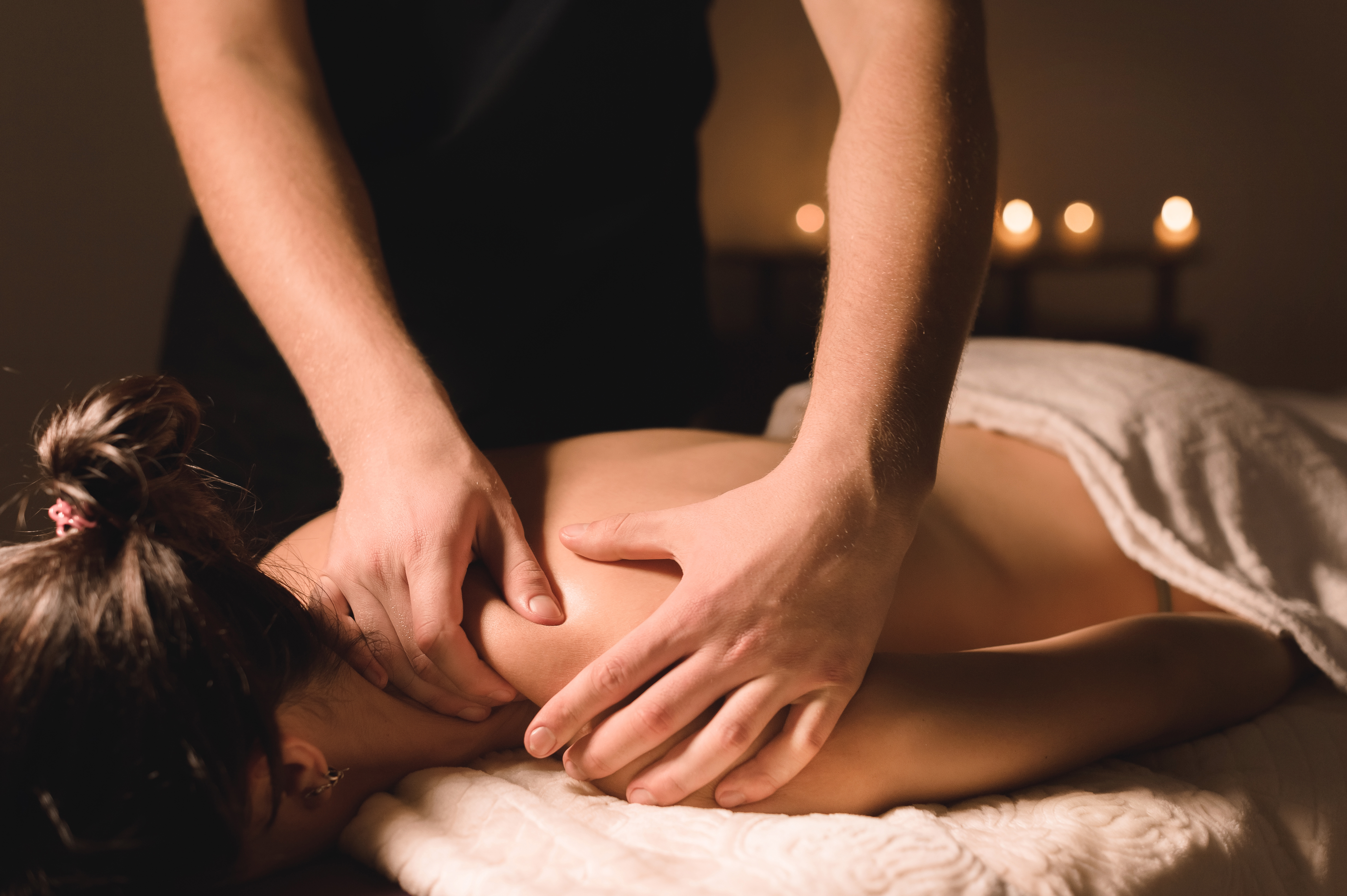 Massage thérapeutique des épaules, ambiance chaleureuse aux chandelles
